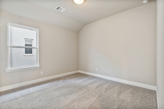 carpeted spare room with visible vents, lofted ceiling, and baseboards