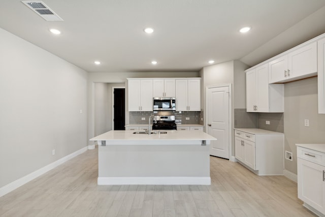 kitchen featuring visible vents, light wood-style flooring, stainless steel appliances, and a sink