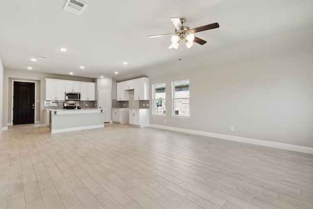 unfurnished living room featuring visible vents, ceiling fan, baseboards, and light wood-style floors