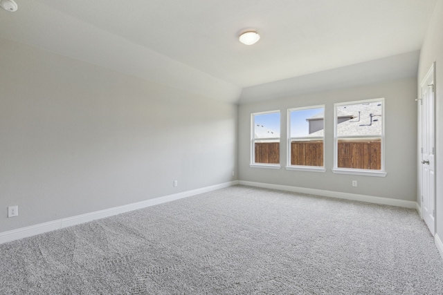 unfurnished room with lofted ceiling, baseboards, and light carpet