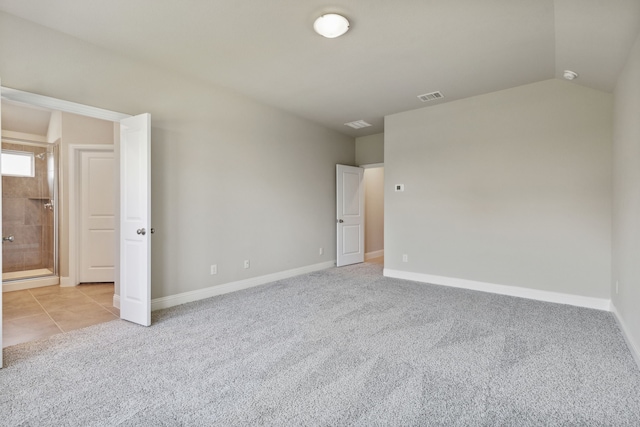 unfurnished bedroom featuring baseboards, visible vents, lofted ceiling, light tile patterned flooring, and light carpet