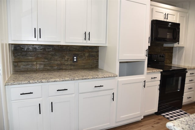 kitchen with light stone counters, wood finished floors, black appliances, white cabinets, and tasteful backsplash