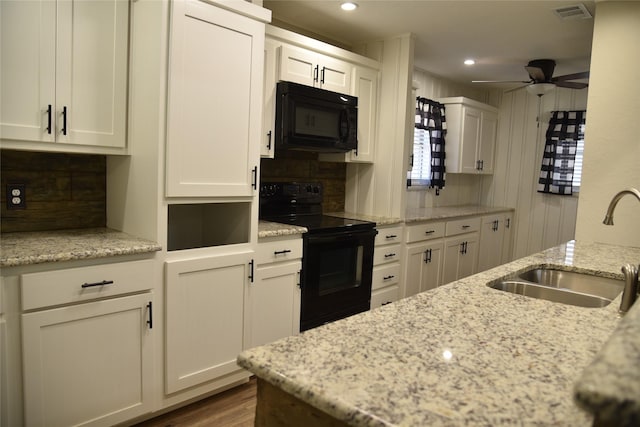 kitchen featuring black appliances, white cabinets, visible vents, and a sink