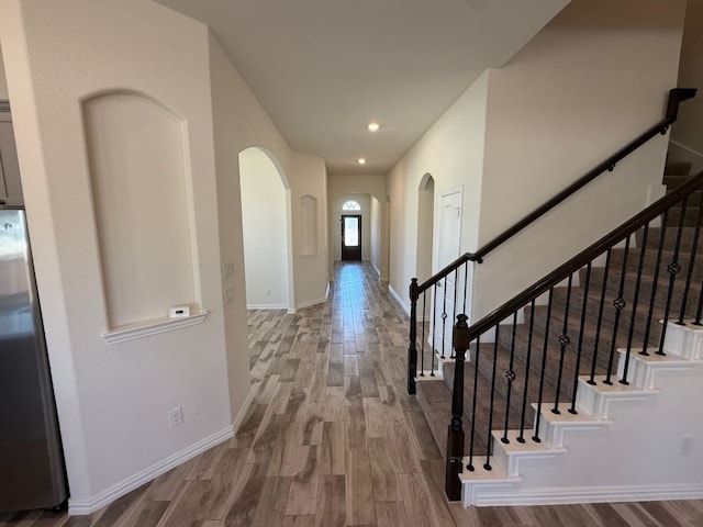 hall featuring recessed lighting, wood finished floors, baseboards, and arched walkways