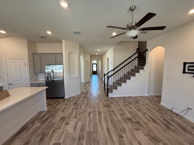 kitchen with visible vents, gray cabinets, stainless steel refrigerator with ice dispenser, arched walkways, and light countertops