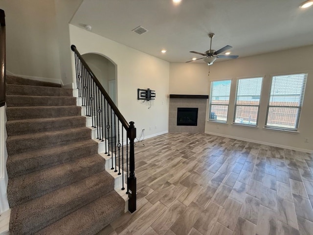 unfurnished living room with a ceiling fan, baseboards, light wood finished floors, recessed lighting, and a fireplace