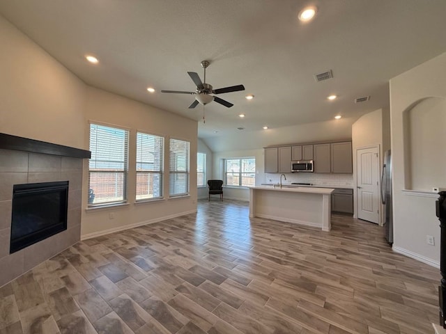 kitchen featuring visible vents, gray cabinets, a tiled fireplace, open floor plan, and stainless steel appliances