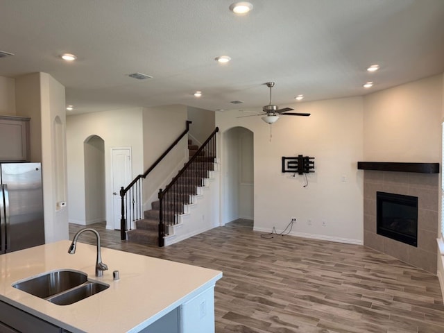 kitchen featuring a fireplace, arched walkways, open floor plan, and a sink