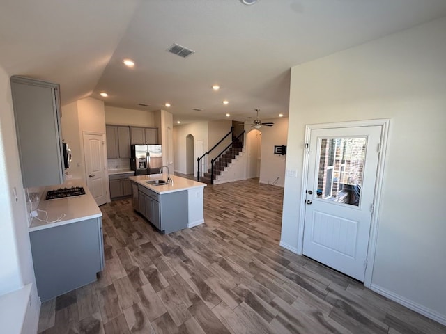 kitchen featuring visible vents, arched walkways, gray cabinets, a sink, and stainless steel appliances