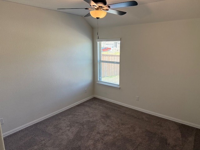 unfurnished room featuring dark carpet, ceiling fan, baseboards, and vaulted ceiling