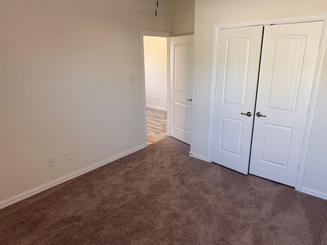 unfurnished bedroom with carpet, a closet, and baseboards