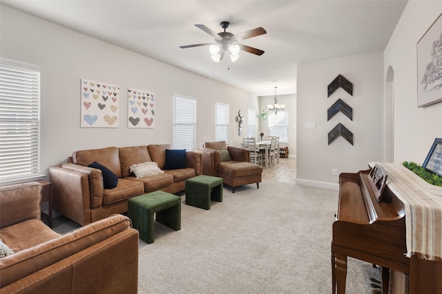 living area featuring light carpet, ceiling fan with notable chandelier, arched walkways, and baseboards