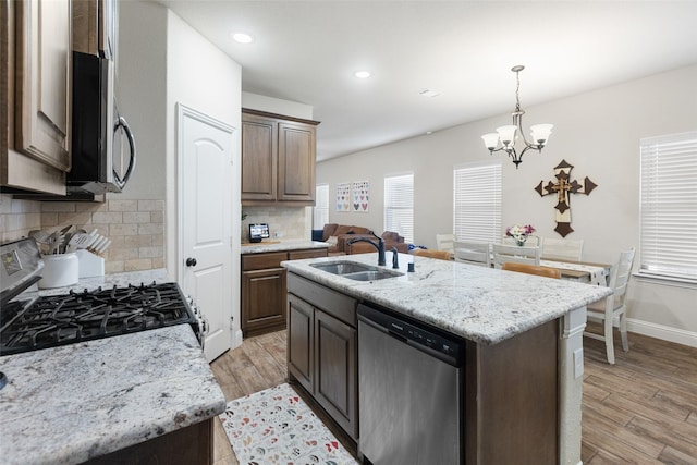 kitchen featuring a sink, light wood-type flooring, backsplash, and stainless steel appliances