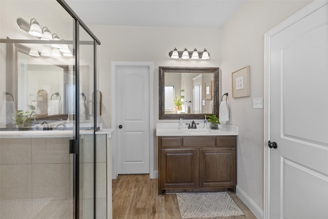 bathroom featuring baseboards, wood finished floors, a stall shower, and vanity