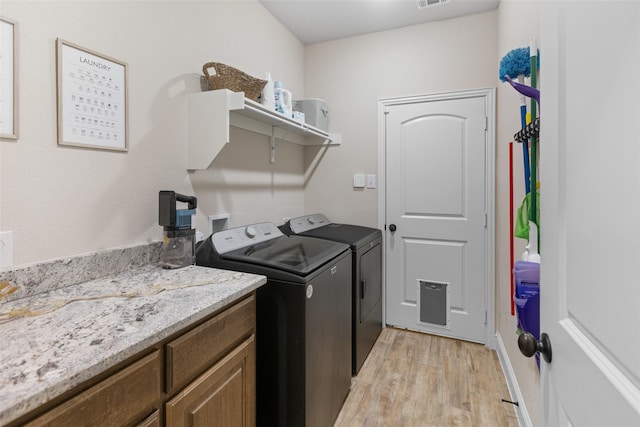 laundry room with visible vents, washing machine and dryer, and light wood-style flooring