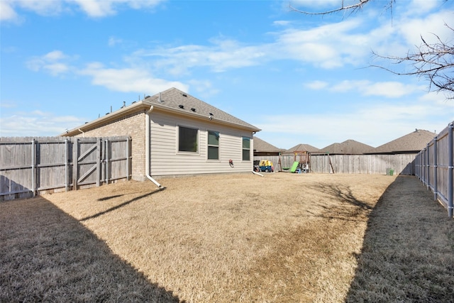 back of property with brick siding, a lawn, a fenced backyard, and roof with shingles