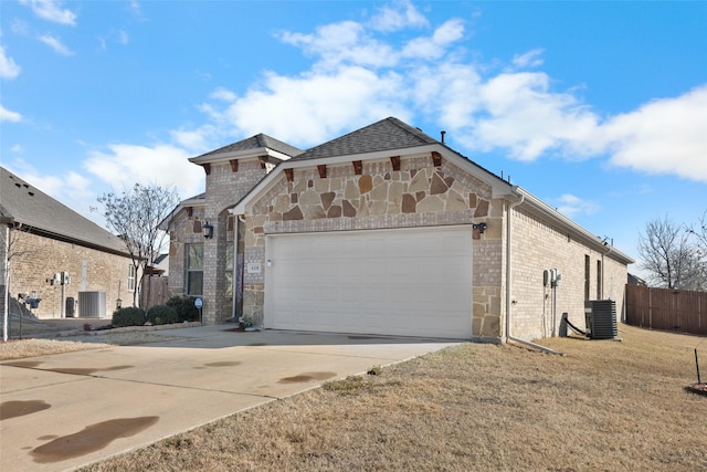 view of front facade featuring driveway, stone siding, fence, a garage, and brick siding