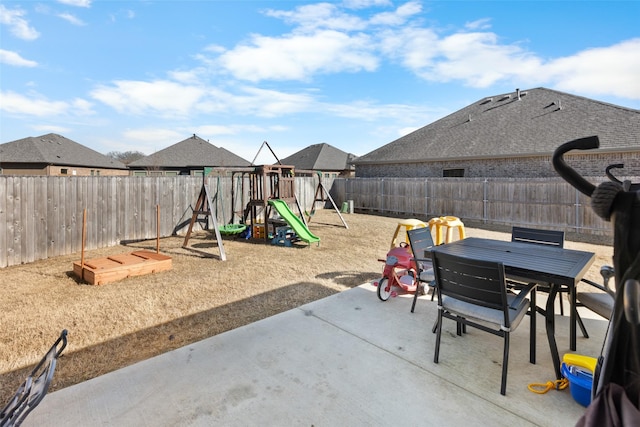 view of patio featuring a playground, outdoor dining area, and a fenced backyard