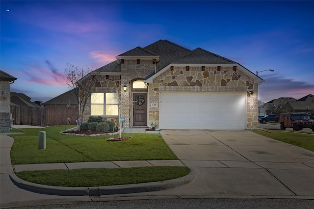 view of front of property with an attached garage, fence, a yard, stone siding, and driveway