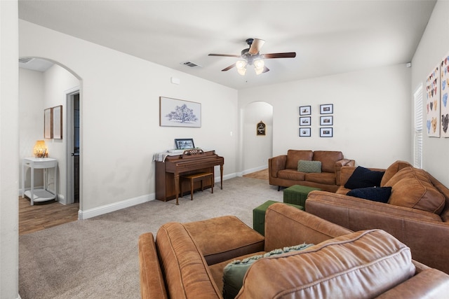 living area with visible vents, arched walkways, carpet floors, and baseboards