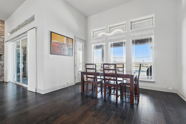 dining space with baseboards, a towering ceiling, and dark wood-style flooring