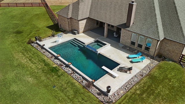 view of pool with a pool with connected hot tub, fence, a yard, a patio area, and a diving board