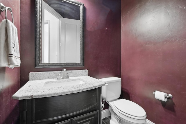 bathroom with baseboards, toilet, and vanity