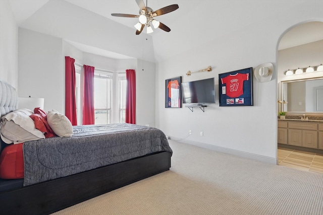 bedroom with a sink, lofted ceiling, light colored carpet, and ensuite bathroom