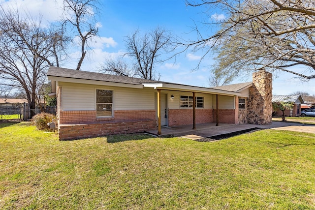 back of property featuring a yard, fence, brick siding, and a chimney