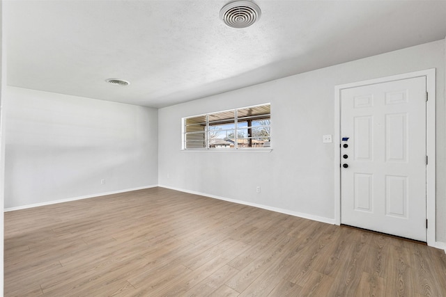 unfurnished room with visible vents, a textured ceiling, baseboards, and wood finished floors