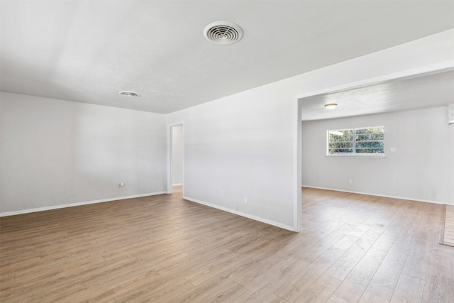 unfurnished room with light wood-type flooring, visible vents, and baseboards