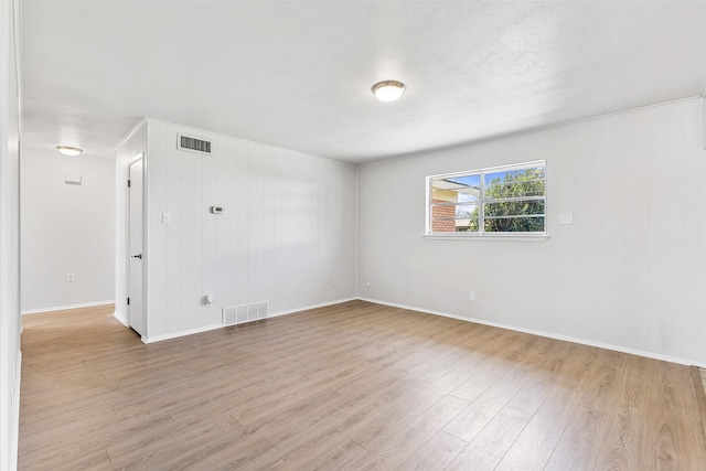 empty room with light wood-style flooring, baseboards, and visible vents