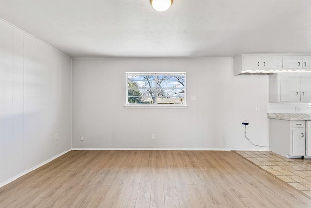 interior space featuring baseboards, crown molding, and light wood finished floors