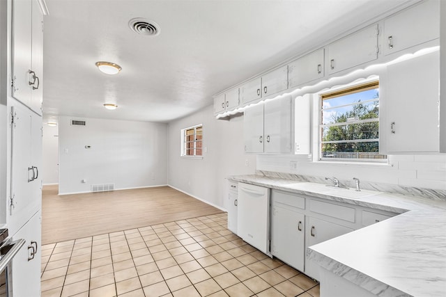 kitchen with a sink, visible vents, backsplash, and white dishwasher