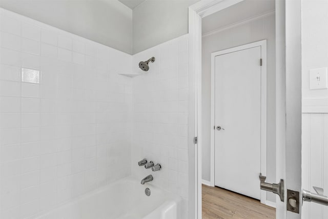 bathroom with ornamental molding, washtub / shower combination, and wood finished floors