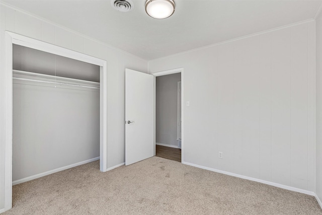 unfurnished bedroom with visible vents, baseboards, ornamental molding, carpet flooring, and a closet