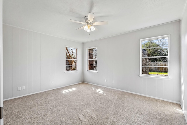 carpeted spare room featuring plenty of natural light, baseboards, and ceiling fan