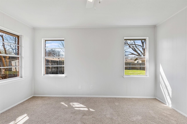 carpeted spare room featuring a healthy amount of sunlight, baseboards, and ornamental molding