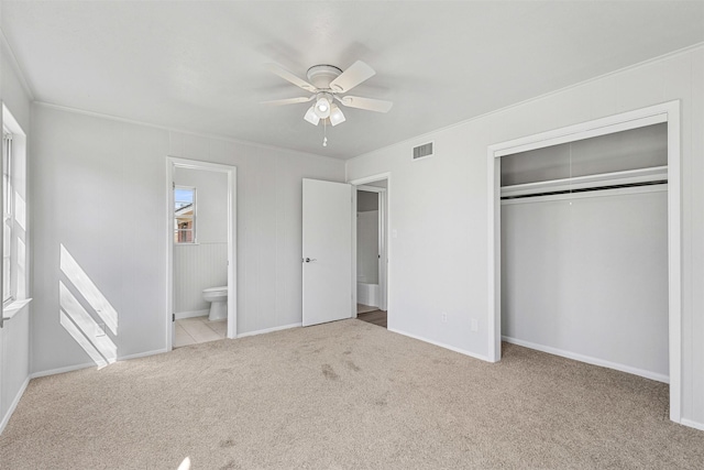 unfurnished bedroom with visible vents, crown molding, carpet flooring, a closet, and ensuite bath