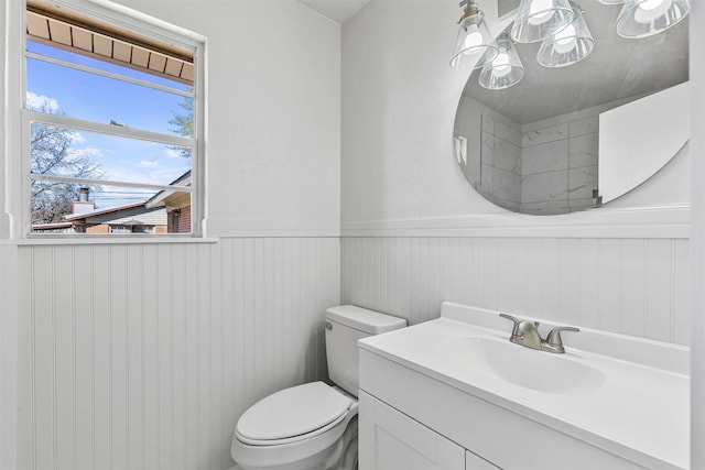 bathroom featuring a wainscoted wall, toilet, and vanity