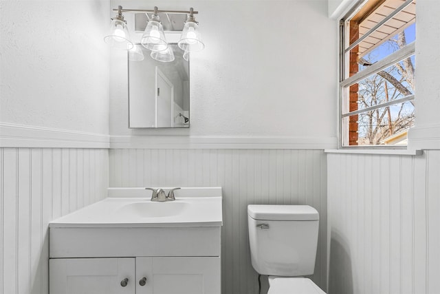 bathroom featuring vanity, wainscoting, and toilet