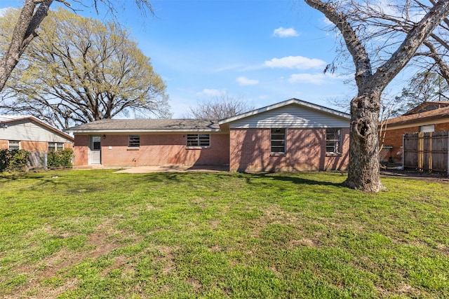 rear view of house with a patio area, a yard, fence, and brick siding