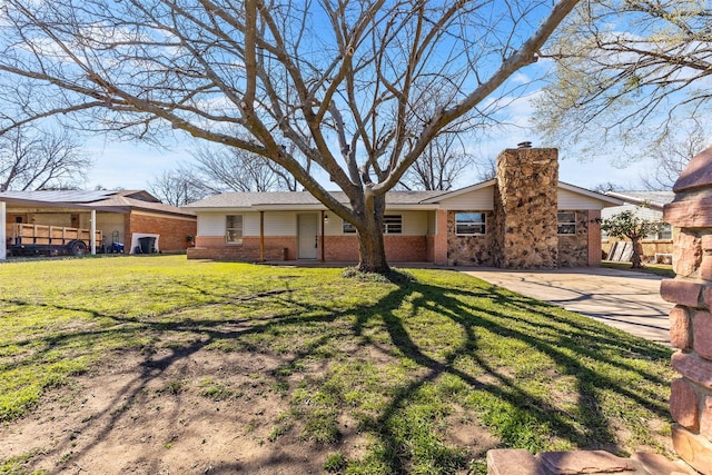 view of front of house featuring driveway, a front lawn, brick siding, and a chimney