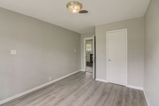 unfurnished bedroom with wood finished floors, visible vents, and baseboards