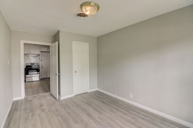 unfurnished bedroom with baseboards, visible vents, a closet, and light wood-type flooring