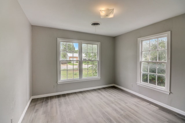 spare room with wood finished floors, baseboards, and visible vents