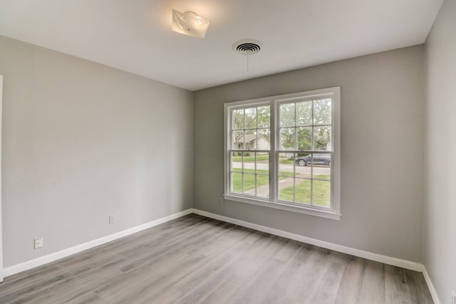 empty room featuring visible vents, baseboards, and wood finished floors