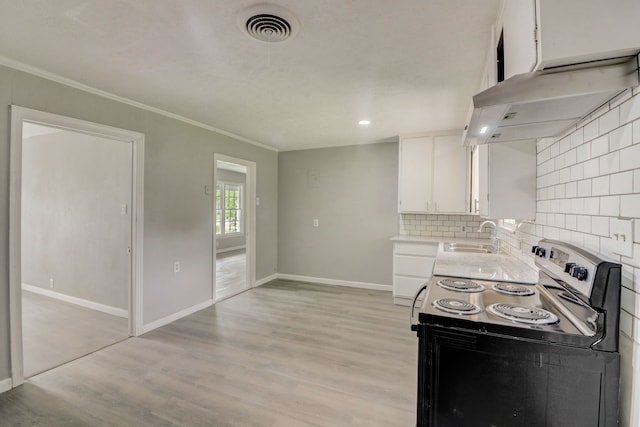 kitchen featuring visible vents, under cabinet range hood, range with electric stovetop, white cabinets, and a sink