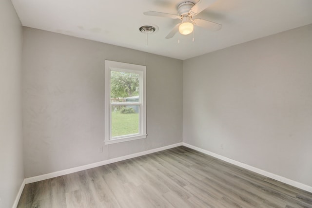 spare room with a ceiling fan, visible vents, baseboards, and light wood finished floors