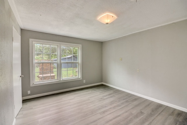 spare room with baseboards, a textured ceiling, and wood finished floors